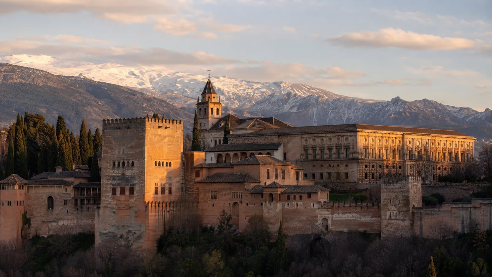 Granada'da Elhamra Sarayı ve arka planda karlı Sierra Nevada dağları, altın saat ışığı